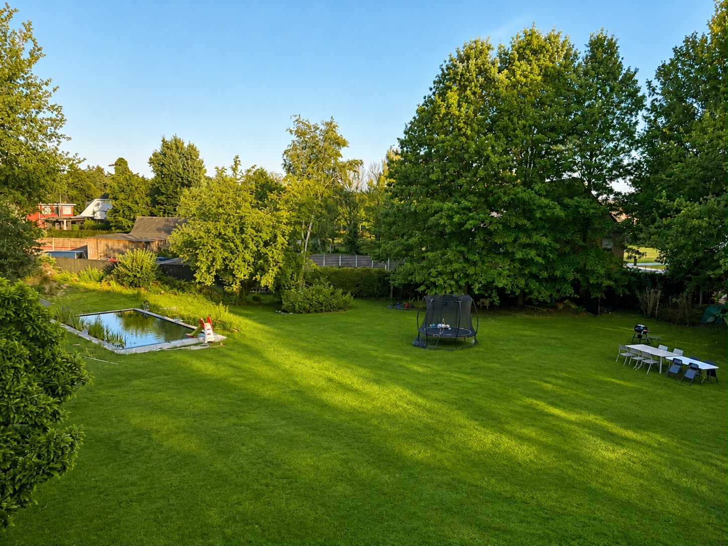 Zicht over de parktuin met zwemvijver en speelweide